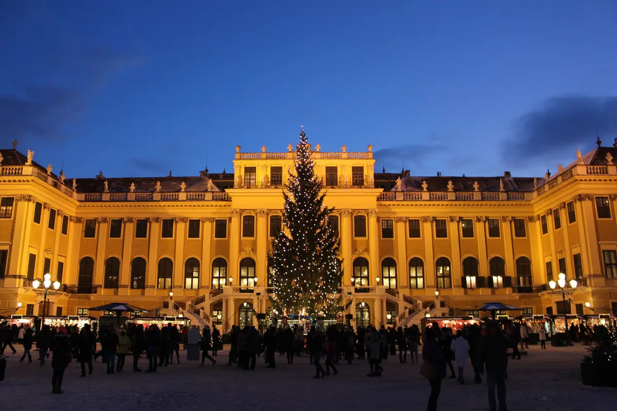 The Christmas market in front of the lit palace at dusk